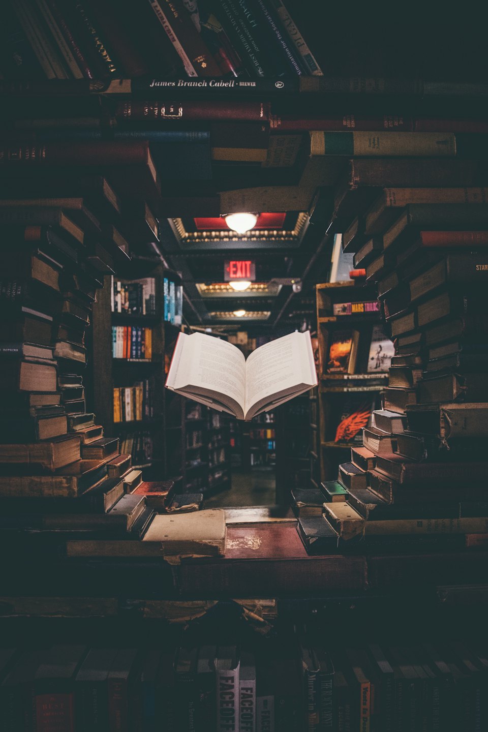 An open book floats in a dimly lit bookstore aisle.